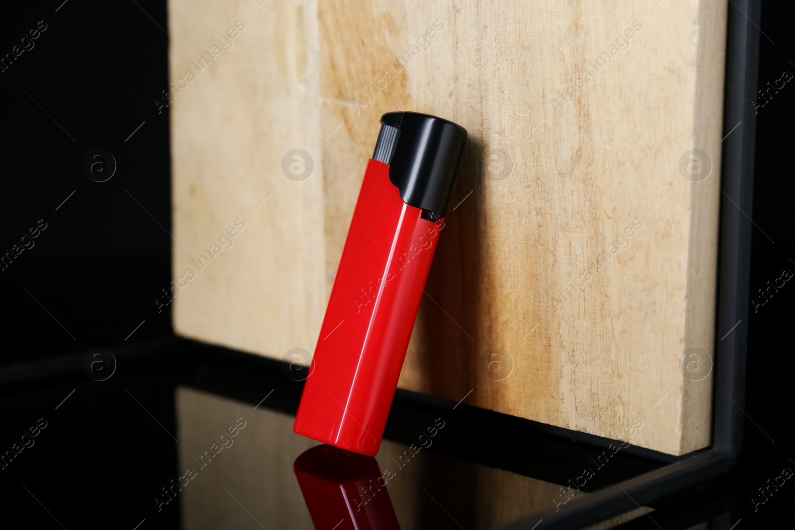Photo of Stylish presentation of red plastic cigarette lighter near wooden surface