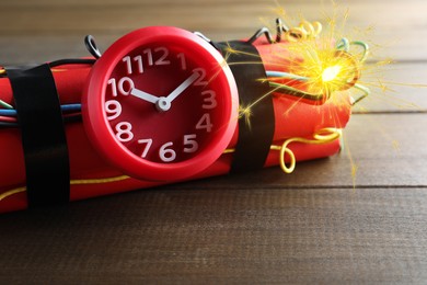 Image of Dynamite time bomb with burning wires on wooden table, closeup