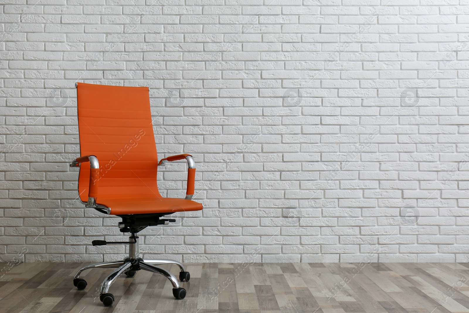 Photo of Comfortable office chair near white brick wall indoors. Space for text
