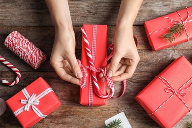 Photo of Woman wrapping Christmas gift at wooden table, top view