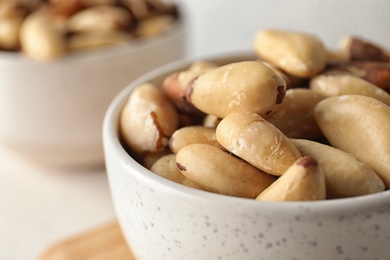 Photo of Bowl with tasty Brazil nuts on table, closeup