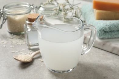 Photo of Glass jug with natural rice water on light grey table