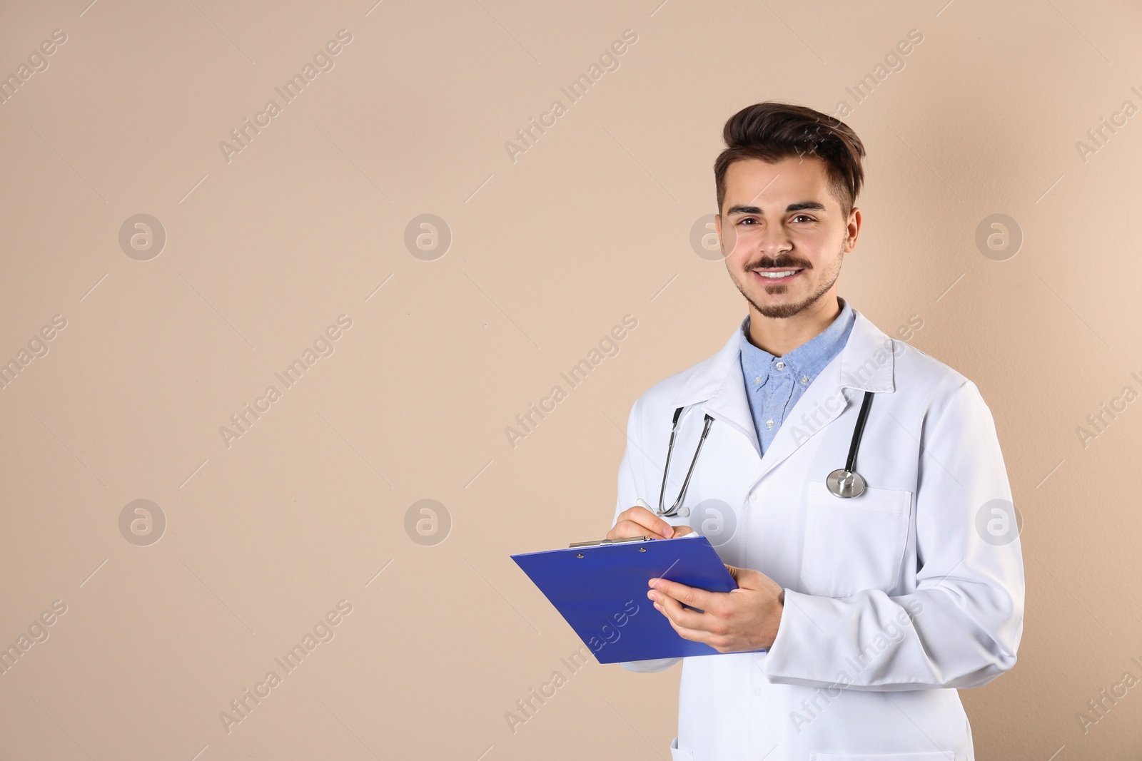 Photo of Young medical student with clipboard on color background. Space for text