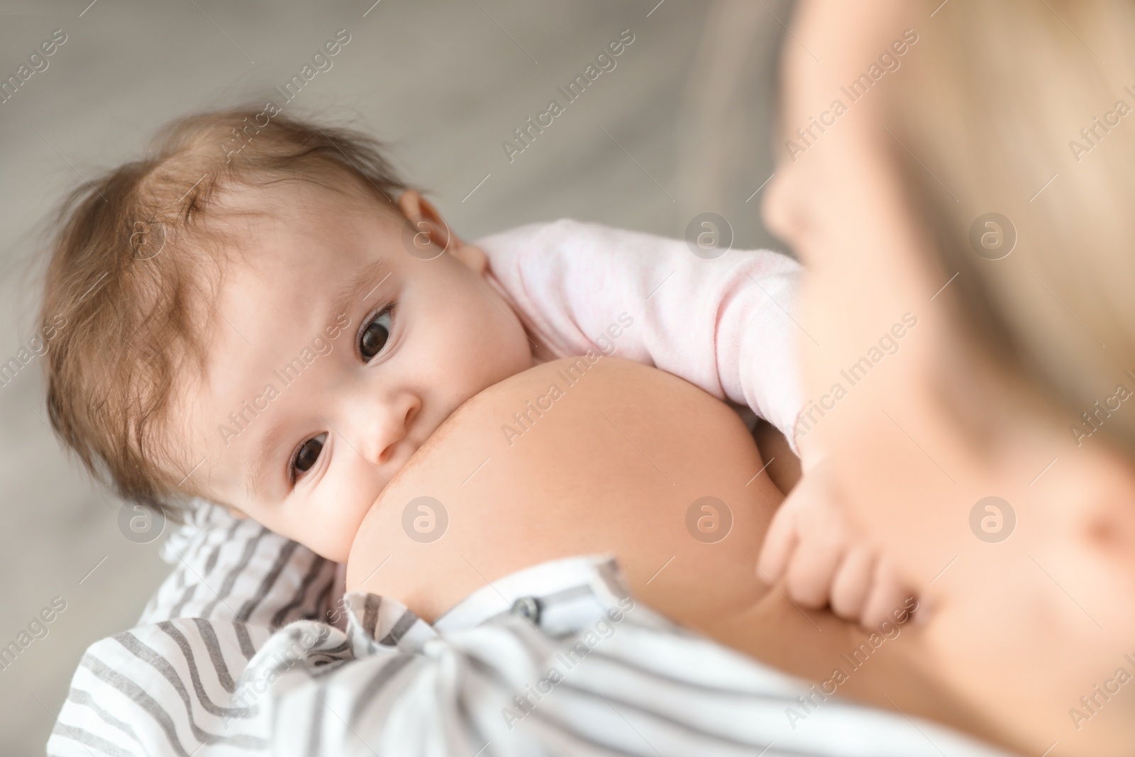 Photo of Young woman breastfeeding her baby at home, closeup