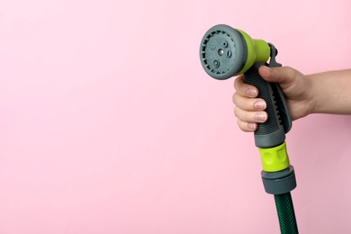Photo of Woman holding watering hose with sprinkler on pink background, closeup. Space for text