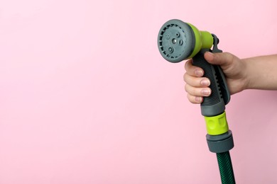 Woman holding watering hose with sprinkler on pink background, closeup. Space for text