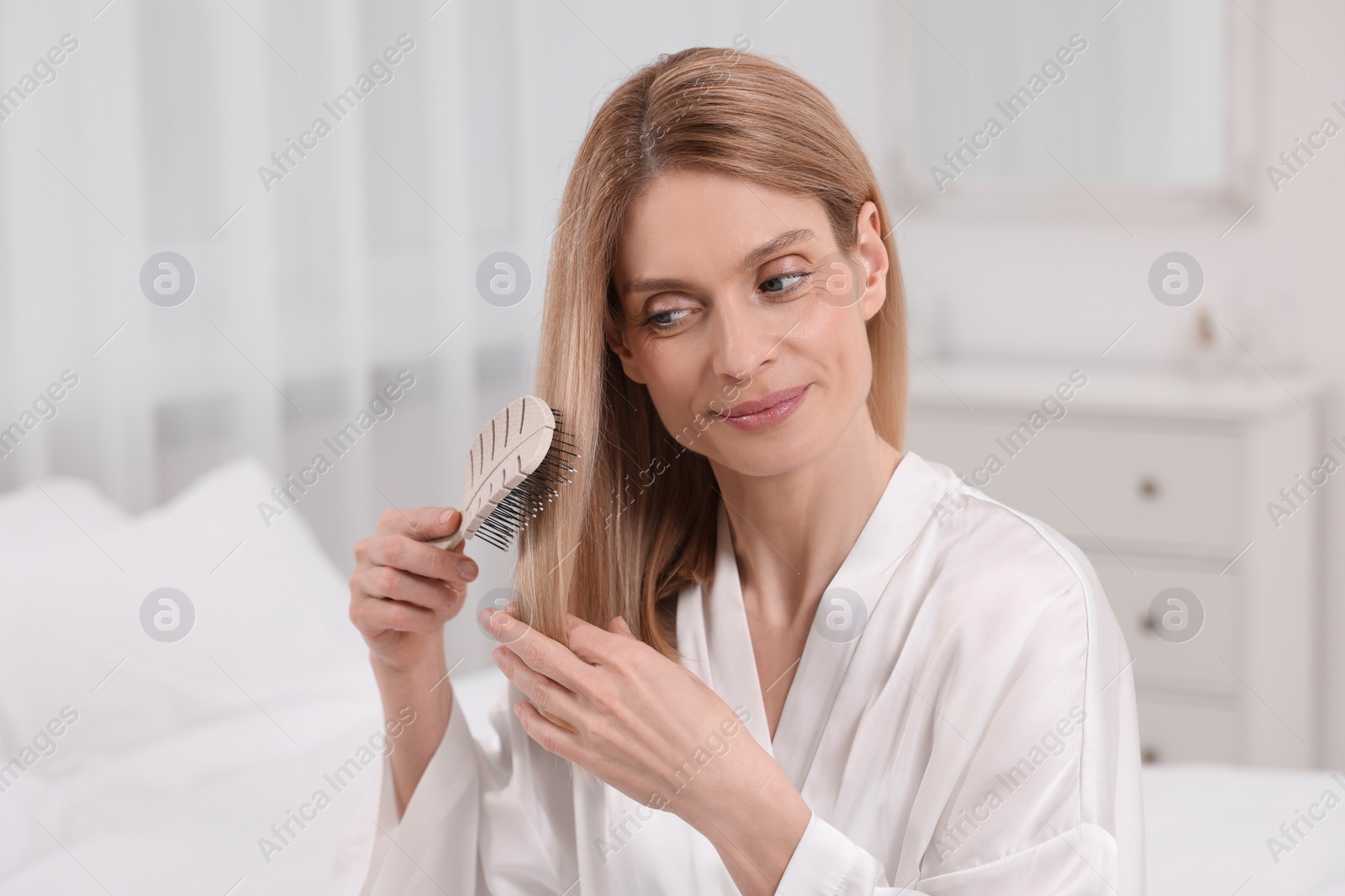 Photo of Beautiful woman brushing her hair in room