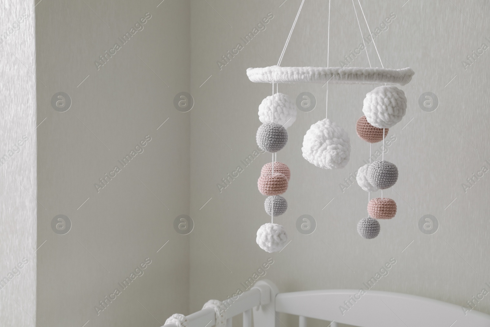 Photo of Modern baby crib mobile near beige wall in room
