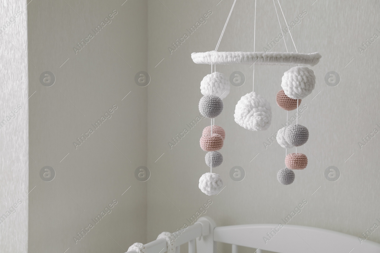 Modern baby crib mobile near beige wall in room Photo of Modern baby crib mobile near beige wall in room