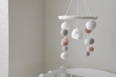 Photo of Modern baby crib mobile near beige wall in room