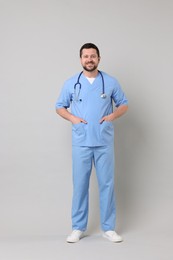 Photo of Full length portrait of smiling doctor on light grey background