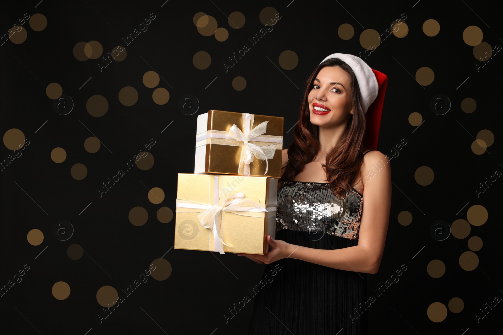 Photo of Beautiful woman wearing Santa hat with Christmas gifts on black background