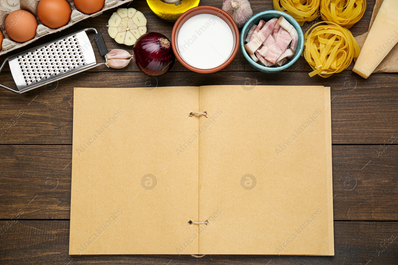 Photo of Blank recipe book and different ingredients on wooden table, flat lay. Space for text