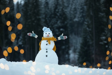 Adorable smiling snowman with Christmas lights outdoors on winter day