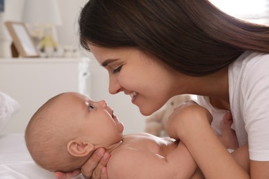 Happy young mother with her cute baby on bed at home