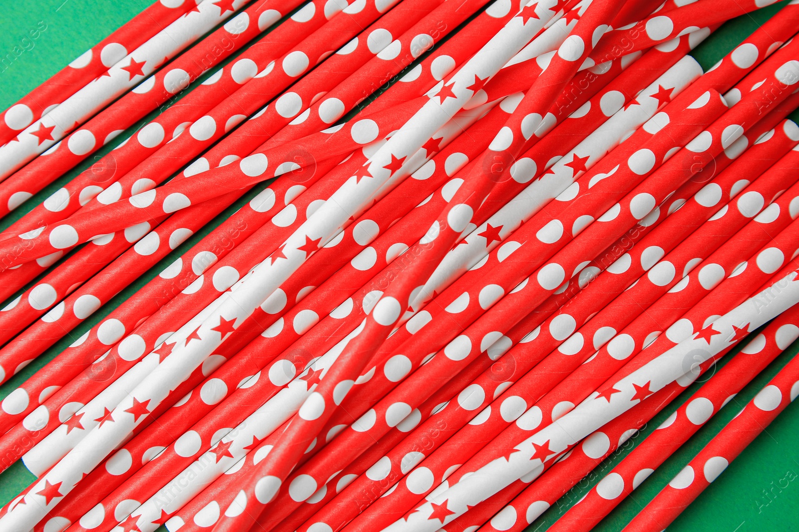 Photo of Many paper drinking straws on green background, above view