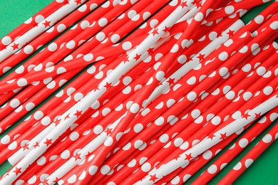 Many paper drinking straws on green background, above view