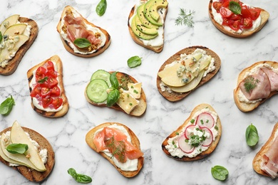 Photo of Different tasty bruschettas on marble background, flat lay