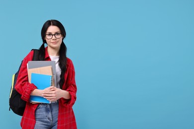 Student with notebooks, folder and backpack on light blue background. Space for text