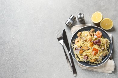 Photo of Delicious pasta with sea food and lemon on grey table, flat lay. Space for text