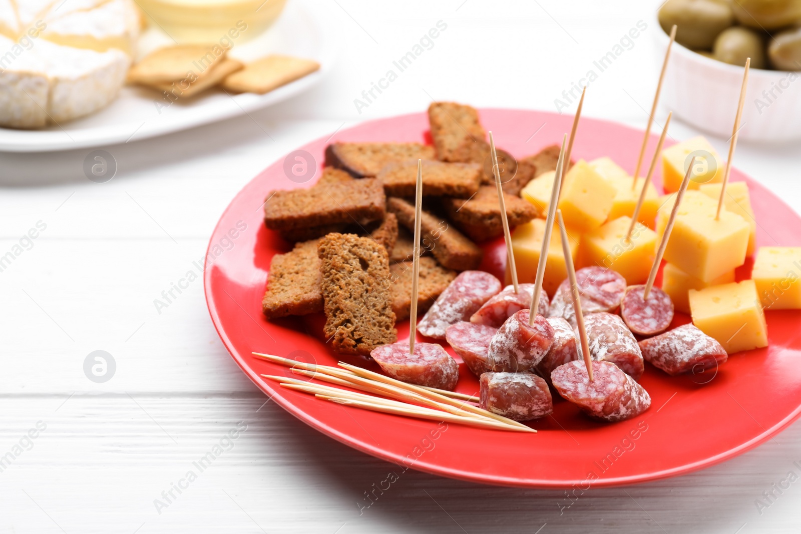 Photo of Toothpick appetizers. Pieces of sausage, cheese and croutons on white wooden table, space for text