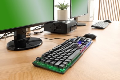Modern computer and RGB keyboard on wooden table indoors
