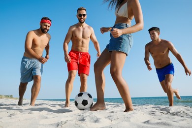 Group of friends playing football on beach