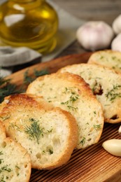 Tasty baguette with garlic, dill and oil on wooden tray, closeup