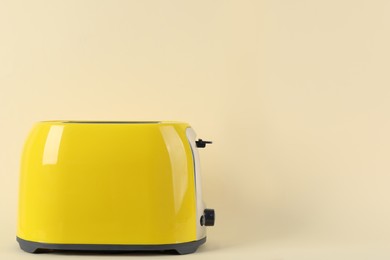 Photo of Modern toaster on beige background. Space for text