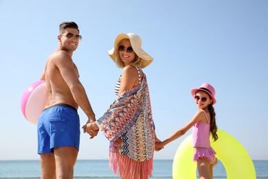 Photo of Happy family with inflatable toys at beach on sunny summer day
