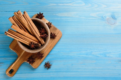 Aromatic cinnamon sticks and anise on light blue wooden table, flat lay. Space for text