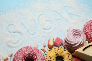 Composition with sweets and word SUGAR on light blue background