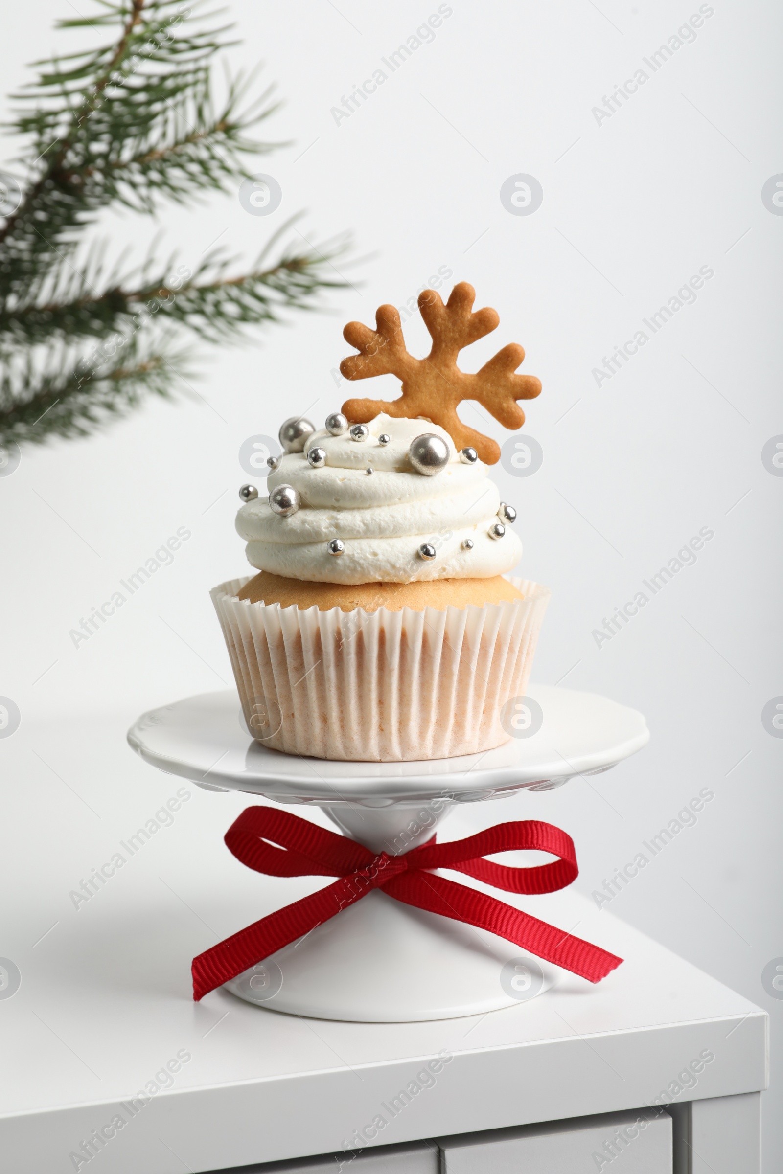 Photo of Tasty Christmas cupcake with cream and snowflake cookie on white table
