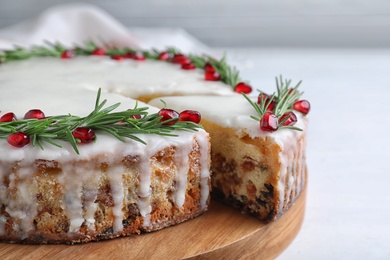 Photo of Traditional Christmas cake decorated with rosemary and pomegranate seeds on white table, closeup