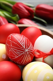 Photo of Bowl with painted Easter eggs on table, closeup