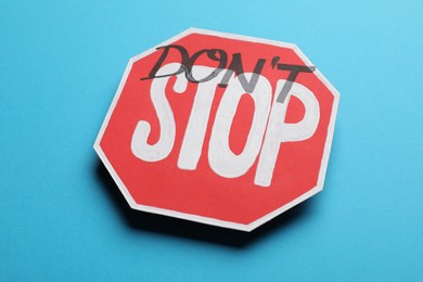 Photo of Don't stop - motivational phrase. Road sign sticker with added written text on light blue background