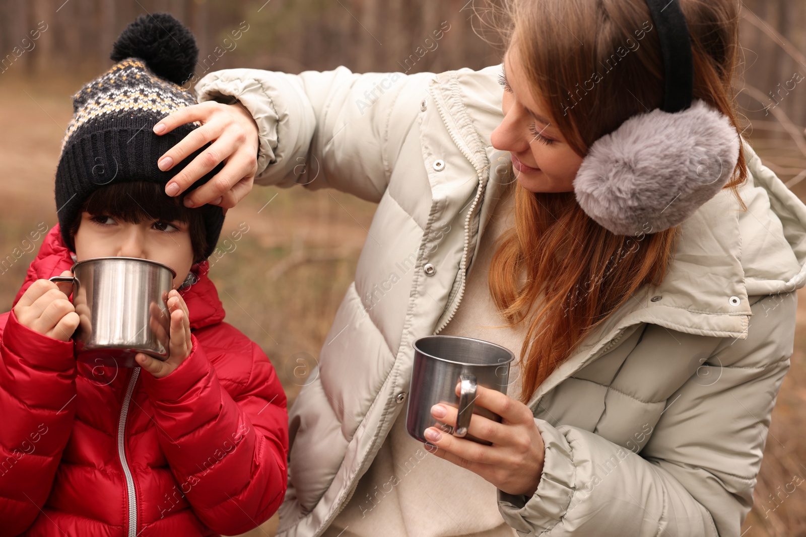Photo of Woman and her son with cups of hot drink in forest
