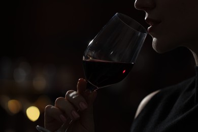 Woman with glass of red wine against blurred background, closeup. Space for text