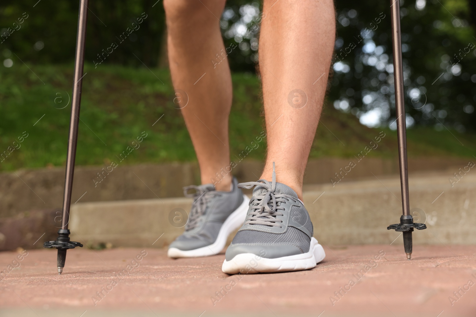 Photo of Man practicing Nordic walking with poles on steps outdoors, closeup