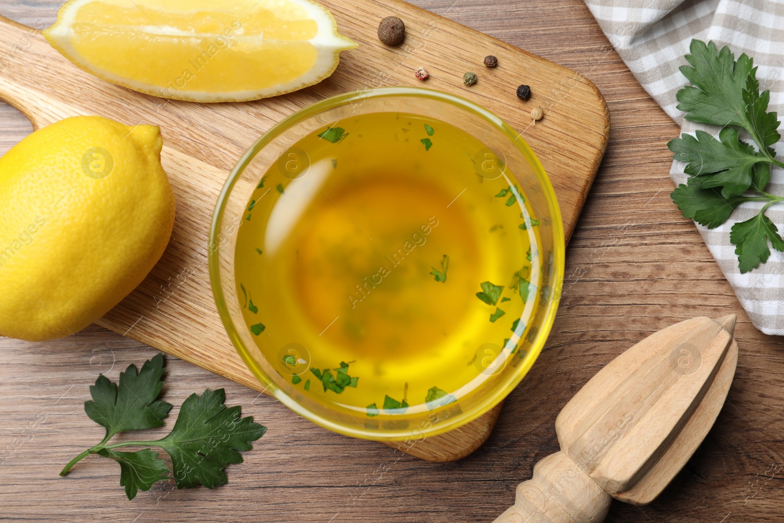 Photo of Bowl with lemon sauce and ingredients on wooden table, flat lay. Delicious salad dressing