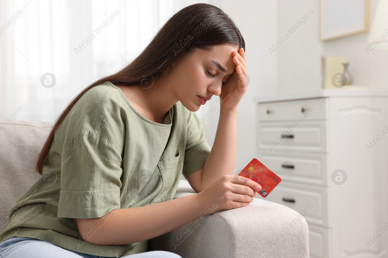 Photo of Stressed woman with credit card at home. Be careful - fraud