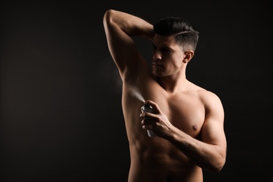 Photo of Handsome man applying deodorant to armpit on black background, space for text
