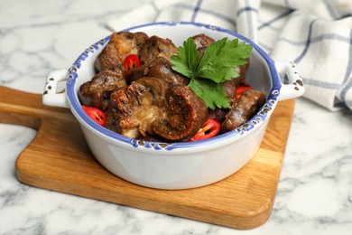 Photo of Bowl with delicious kidneys, pepper and parsley on white marble table