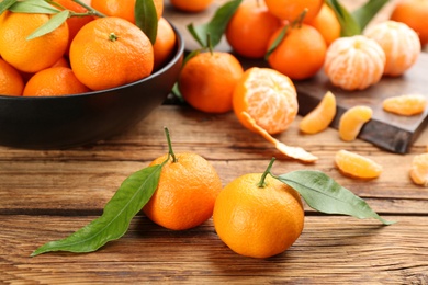 Fresh ripe tangerines with green leaves on wooden table