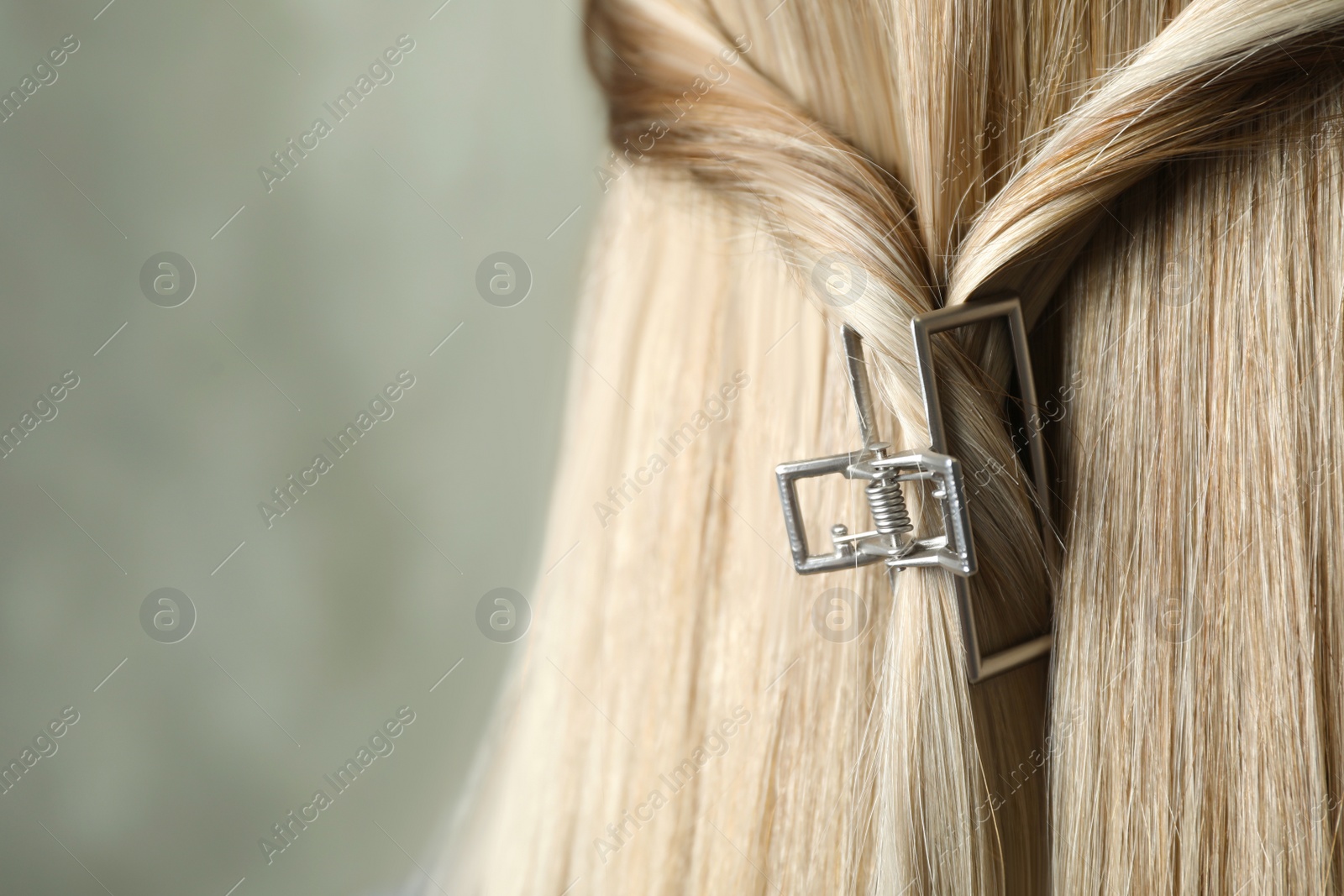 Photo of Young woman with beautiful hair claw on grey background, closeup