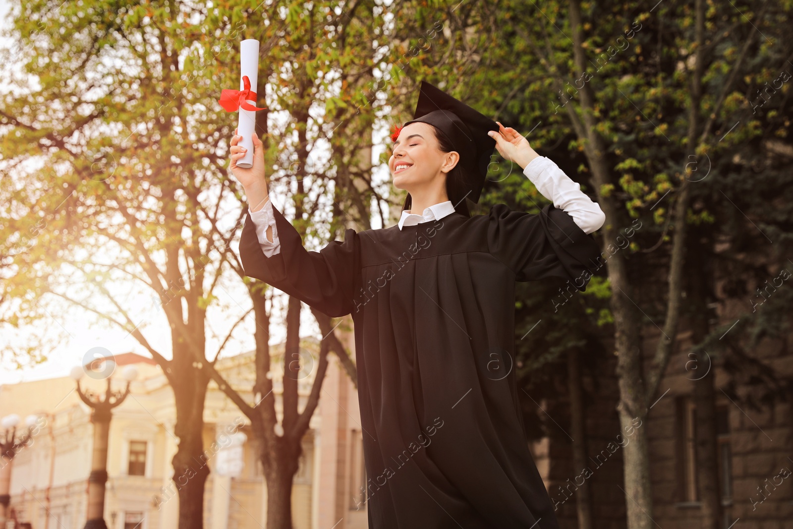 Photo of Happy student with diploma after graduation ceremony outdoors