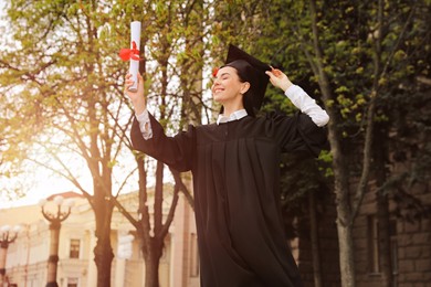 Happy student with diploma after graduation ceremony outdoors