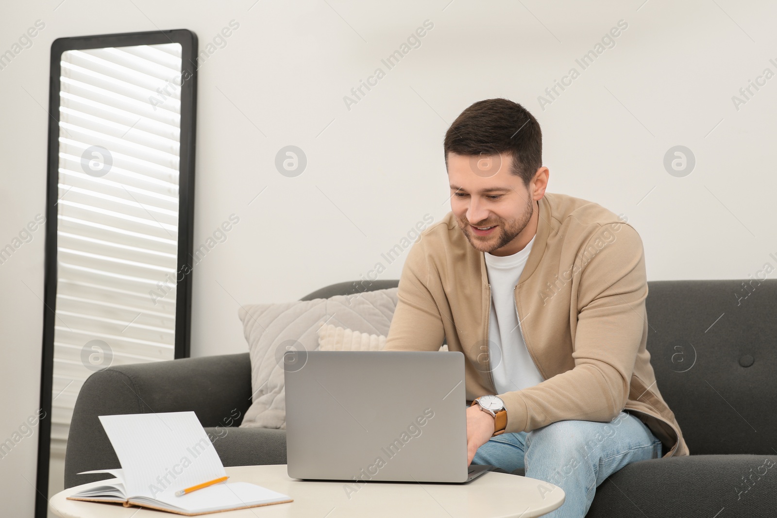 Photo of Man working with laptop at table in living room