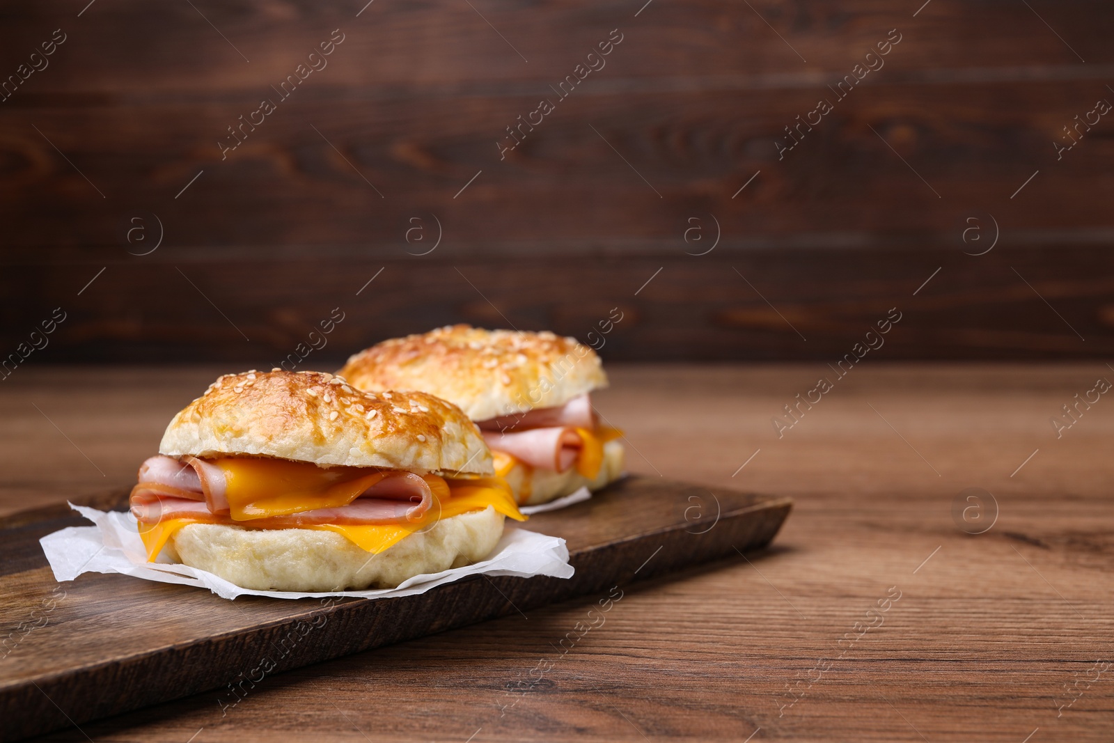 Delicious bagels with ham and cheese on wooden table. Space for text Photo of Delicious bagels with ham and cheese on wooden table. Space for text