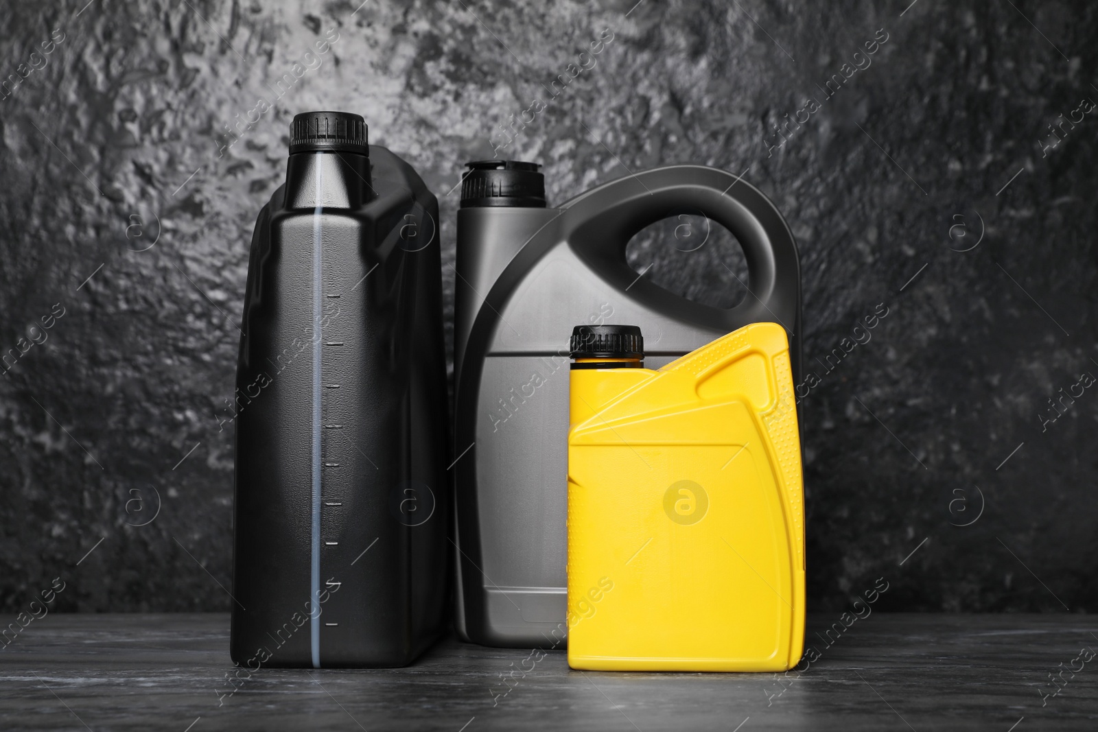 Photo of Motor oil in different canisters on black table near dark wall